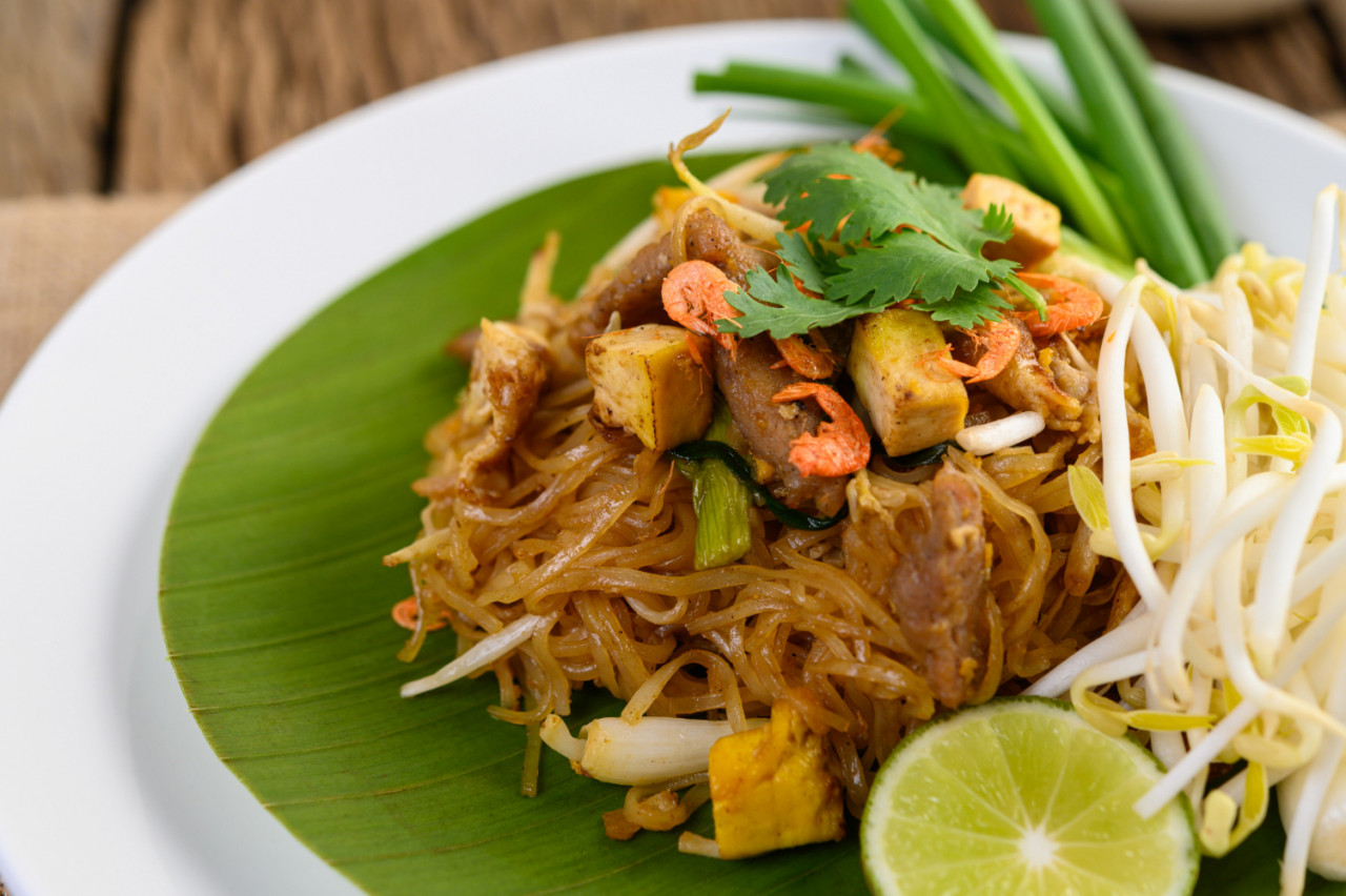 pad thai white plate with lemon wooden table