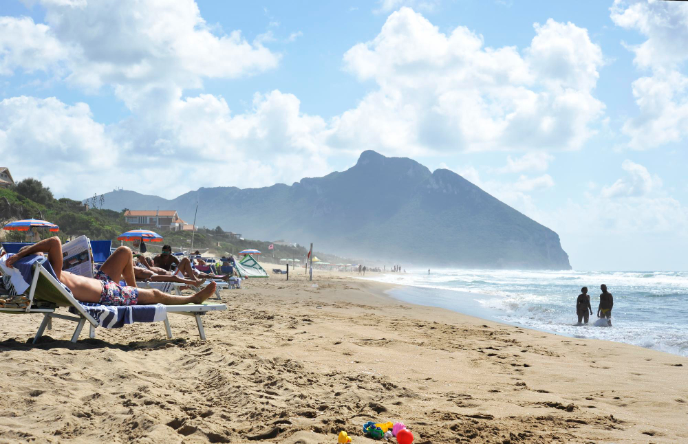 persone rilassate sulla spiaggia di sabaudia per le vacanze estive il monte circeo sullo sfondo sabaudia lazio italia