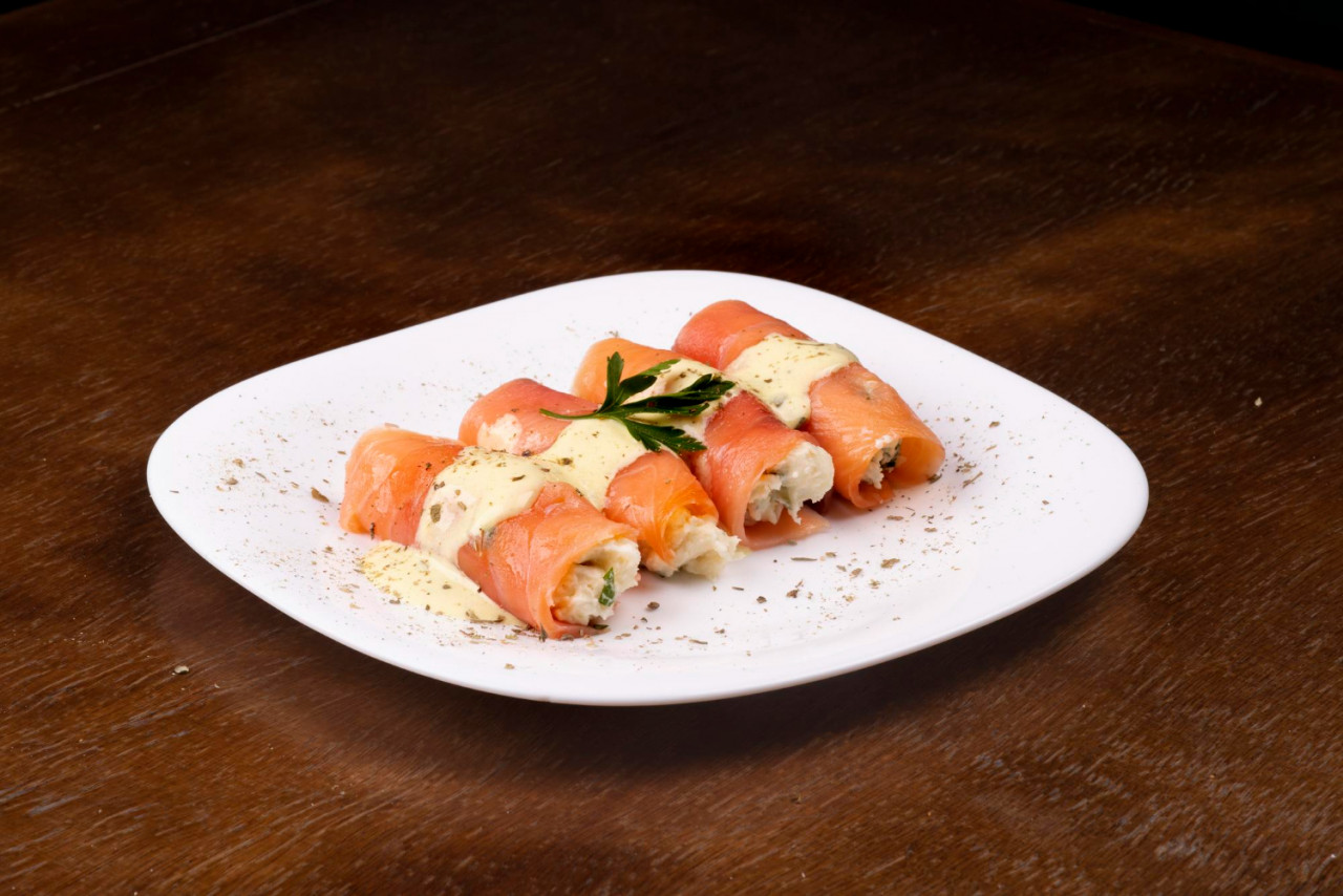 plate fresh smoked salmon rolled up stuffed with cream cheese parsley wooden table