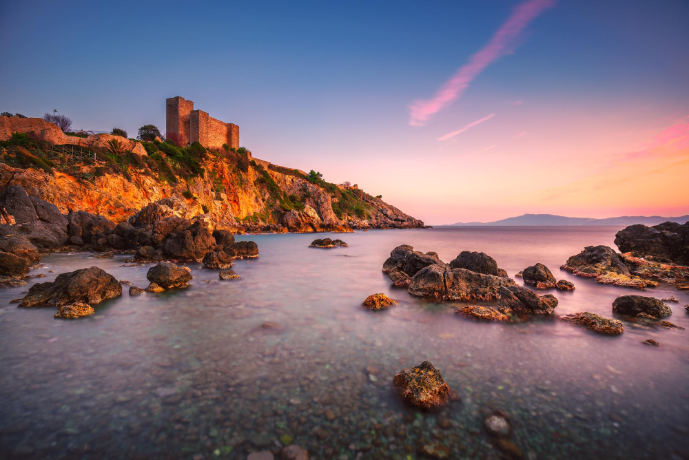 playa rocosa de talamone y la fortaleza medieval al atardecer maremma argentario toscana italia