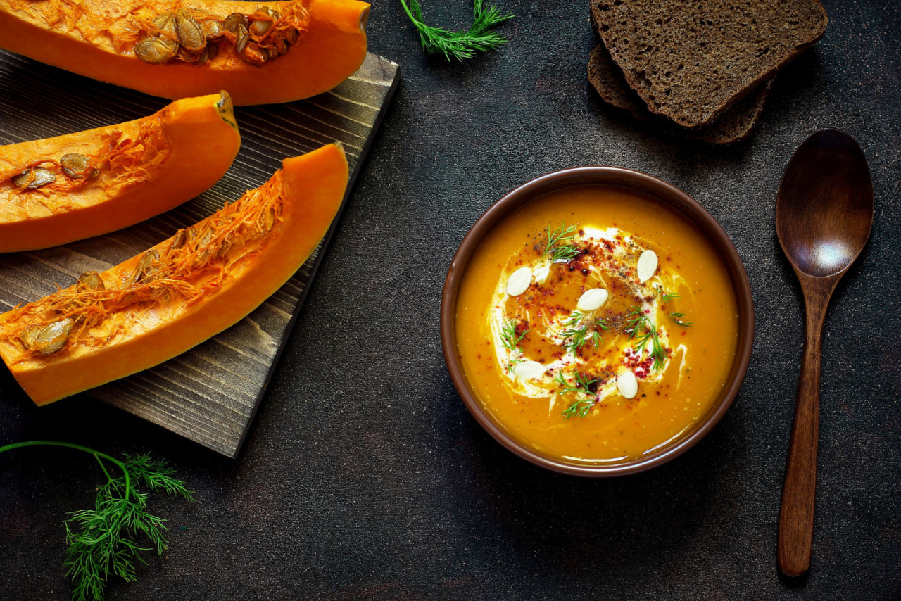 roasted pumpkin carrot soup with cream seeds fresh green ceramic bowl top view