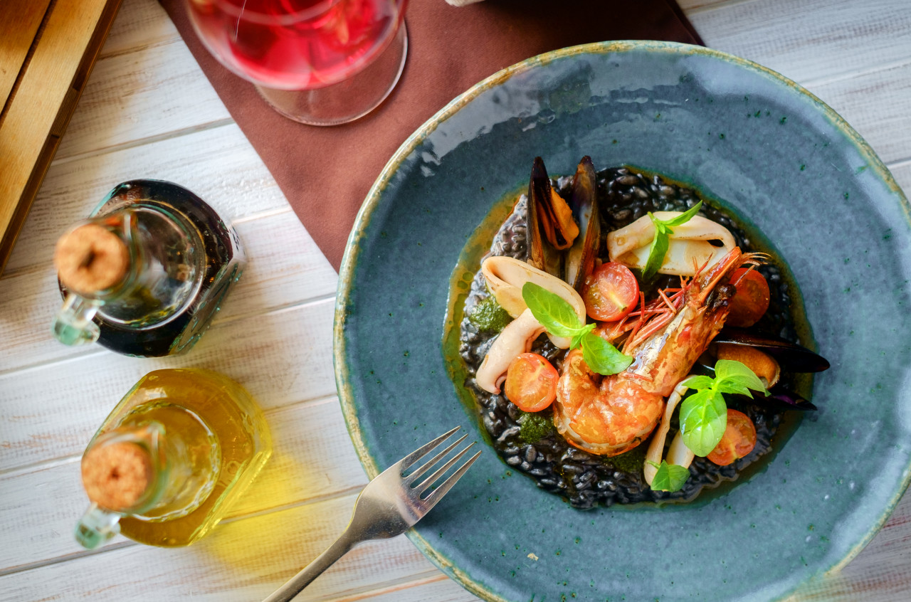 seafood risotto black plate wooden table top view