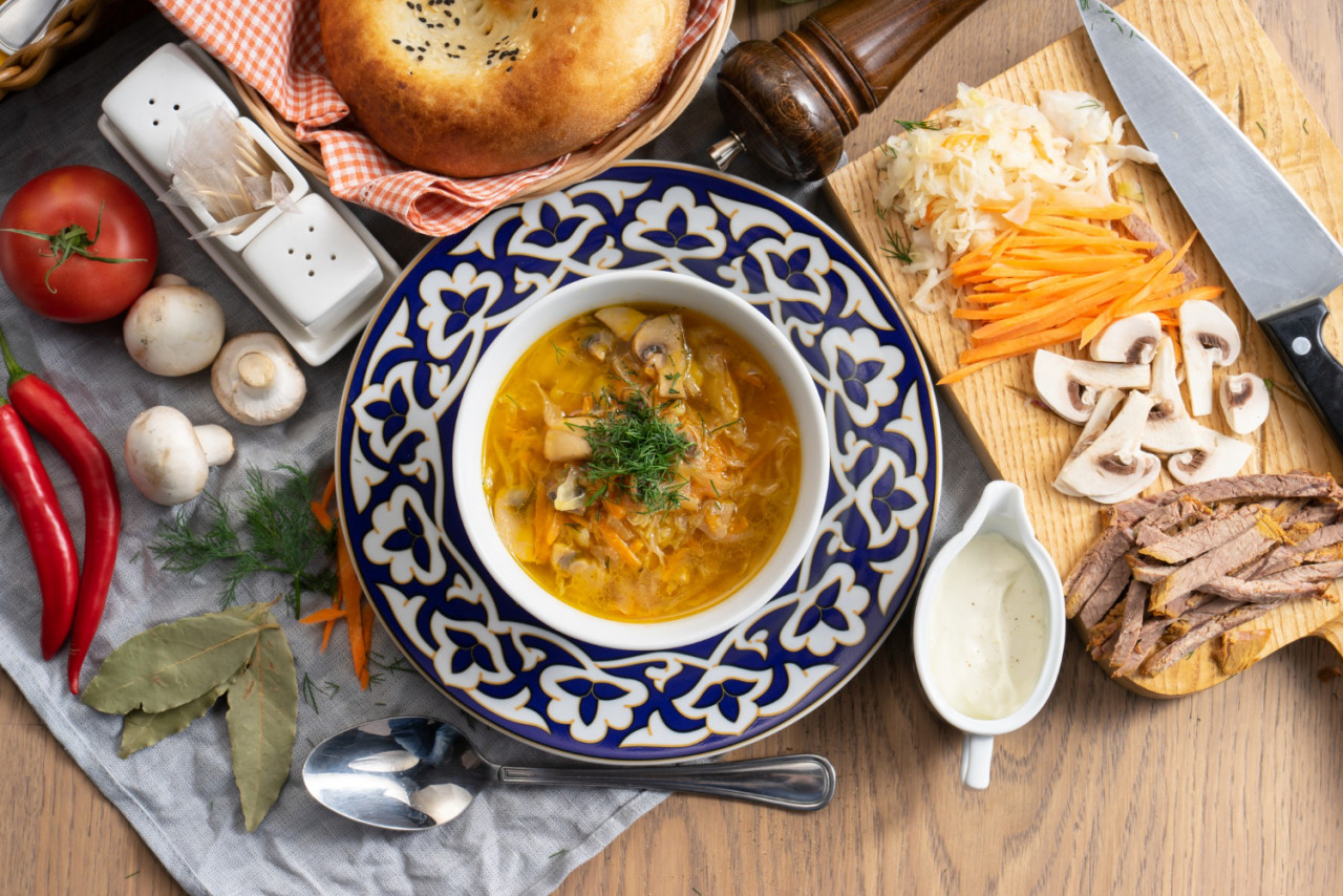 shchi with sour cream a traditional russian vegetable soup made of cabbage potatoes carrots and mushrooms in a plate with a traditional uzbek