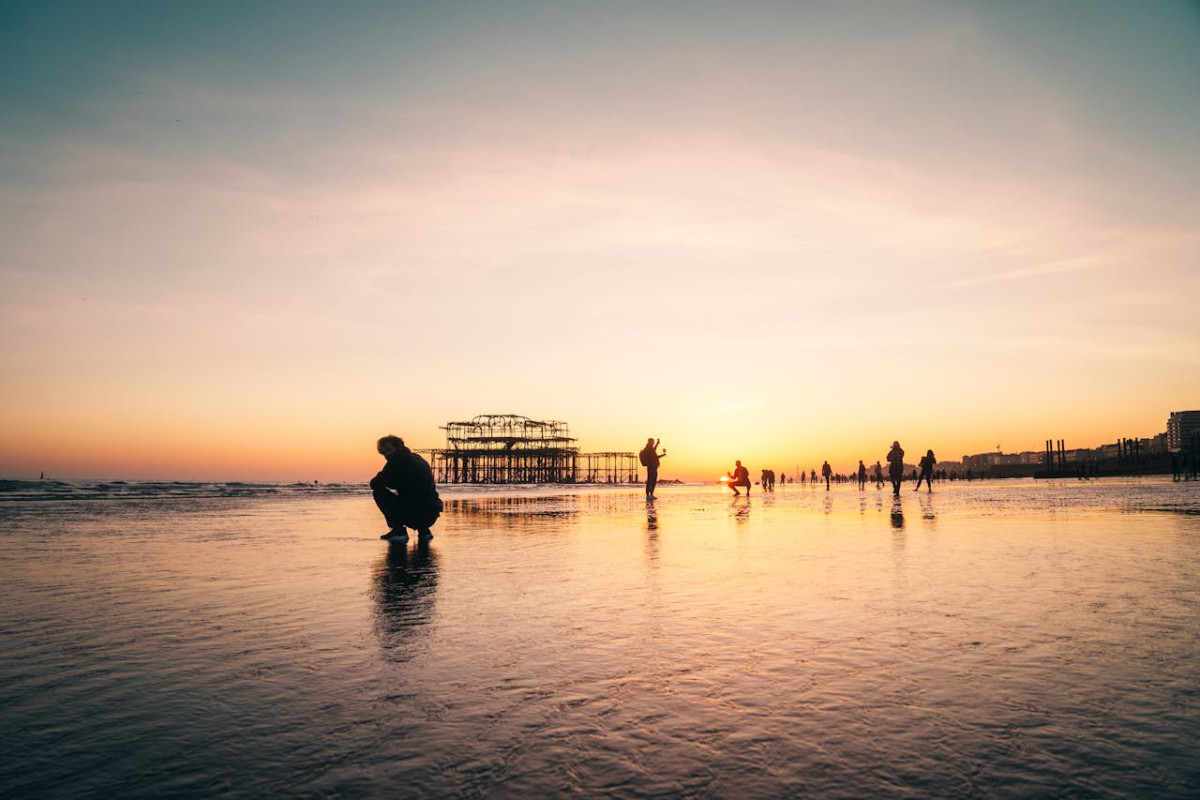 silhouette of man sitting on beach during sunset