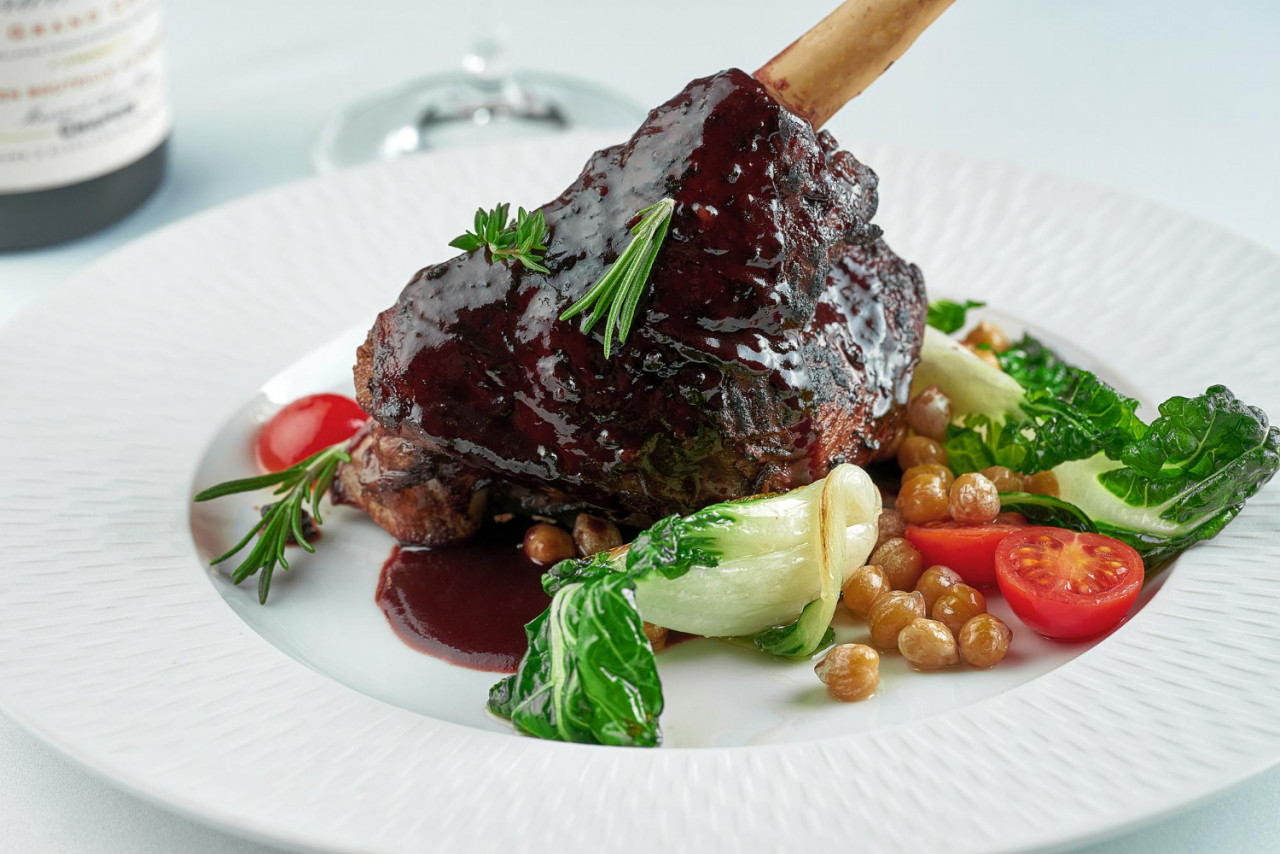 slow cooked lamb shank wine sauce white plate white tablecloth