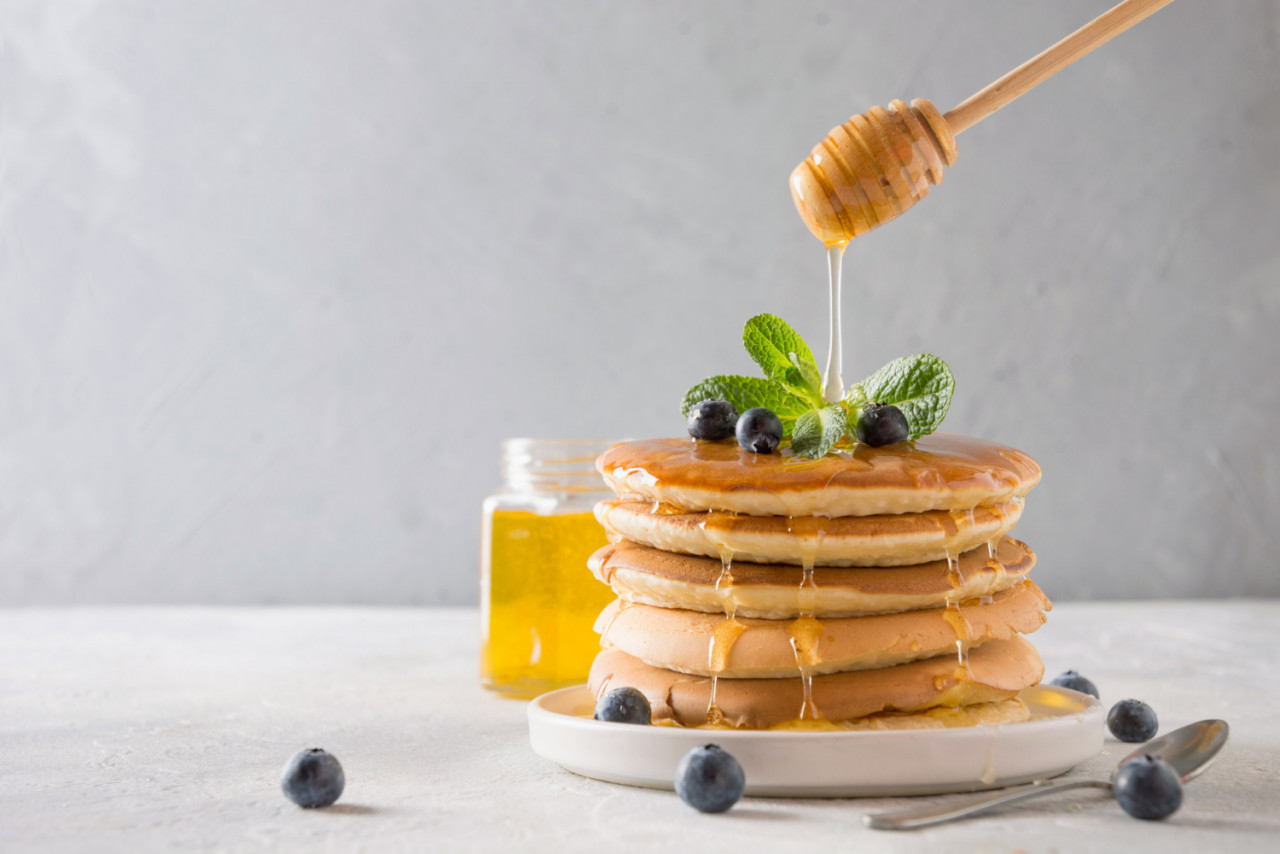 stack pancakes with pouring honey fresh blueberry mint light wall