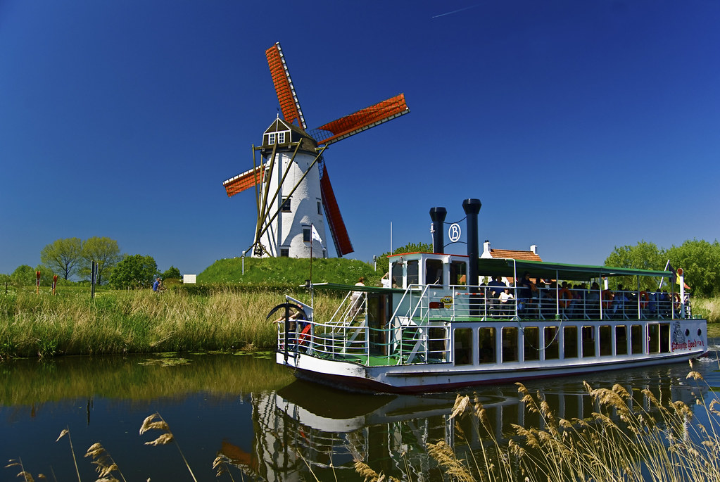 Canale alberato e mulini a vento nel villaggio rurale di Damme.