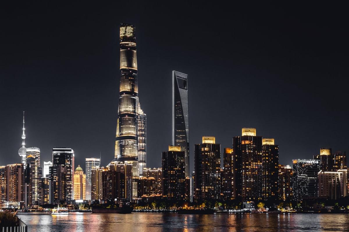 the illuminated shanghai tower with city buildings at night