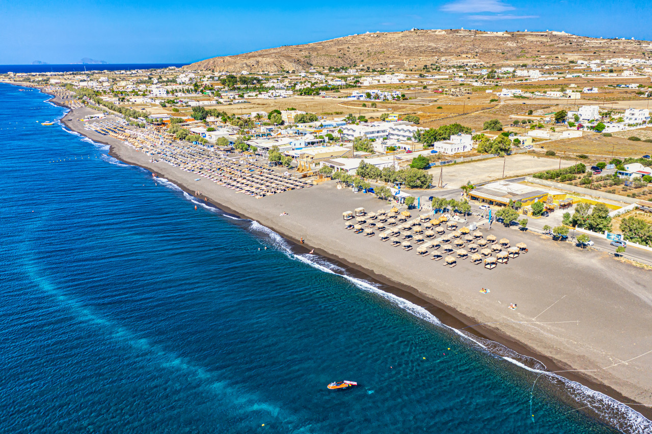 top view aerial drone photo black perissa beach with beautiful turquoise water sea waves straw umbrellas vacation travel background aegean sea santorini island greece