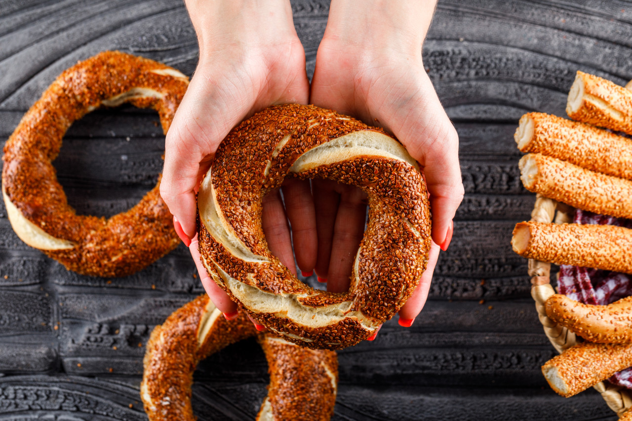 top view woman holding turkish bagel dark wooden surface horizontal