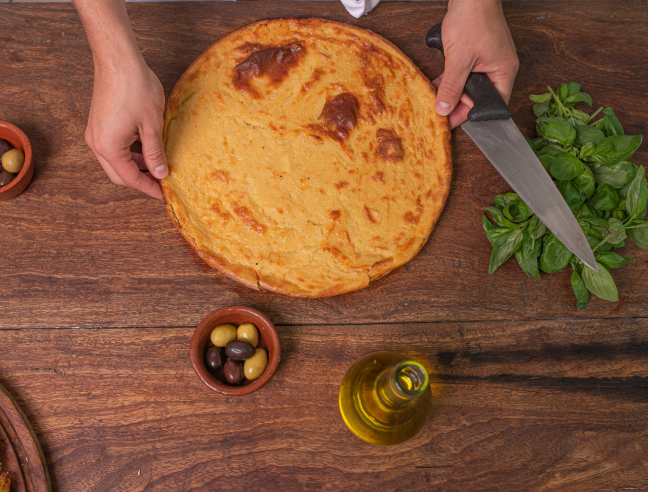 top view women s hands with typical faina pizza made from chickpea flour