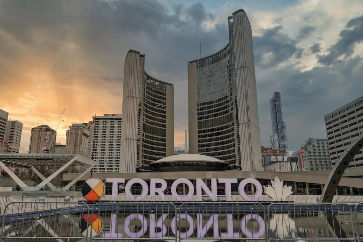 toronto signage near buildings under white clouds