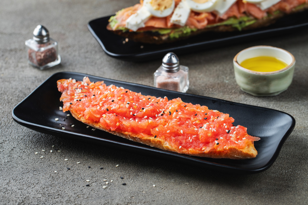 traditional spanish breakfast tostada with different toppings dark background