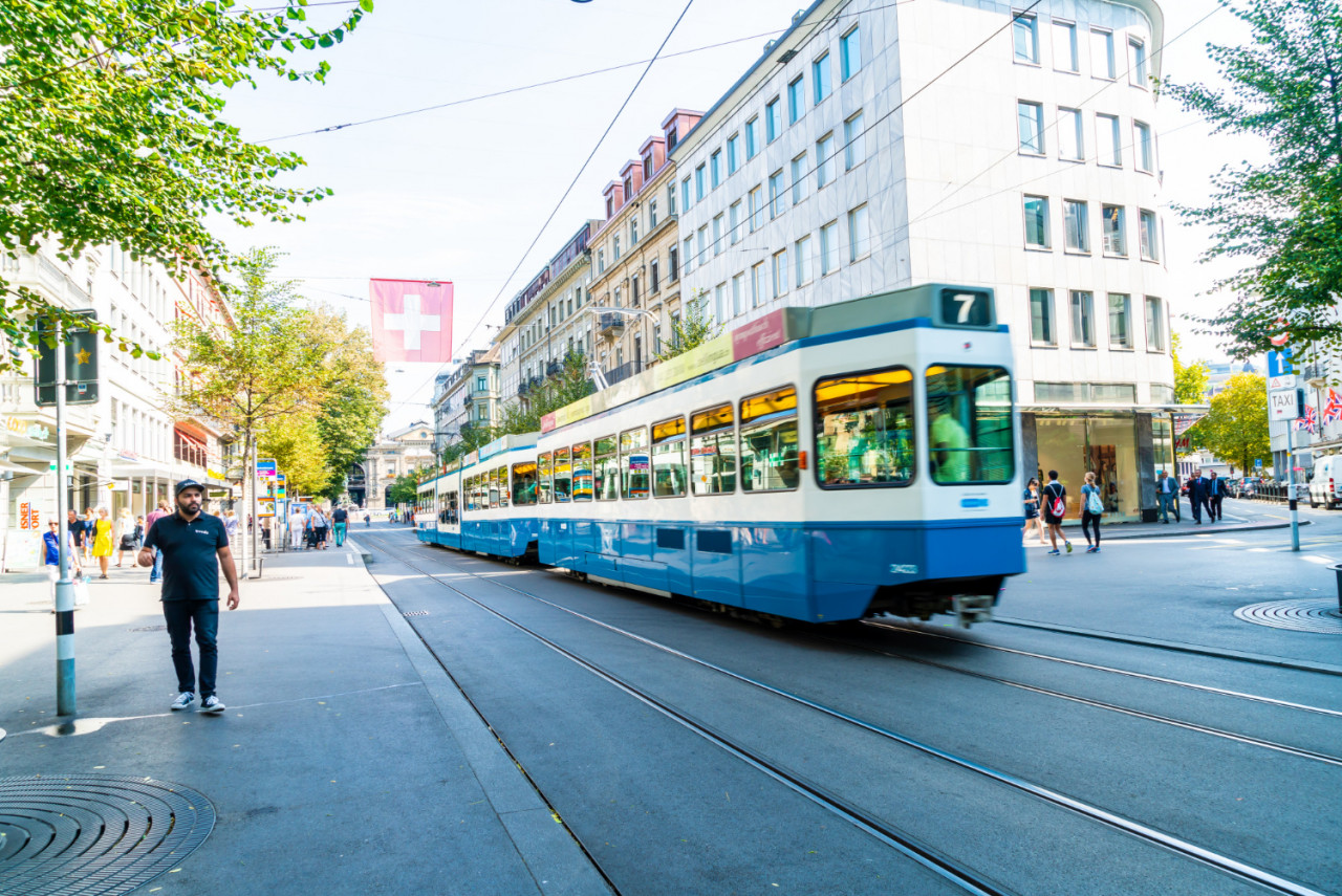 tram drives down center bahnhofstrasse while people walk sidewalks zurich switzerland