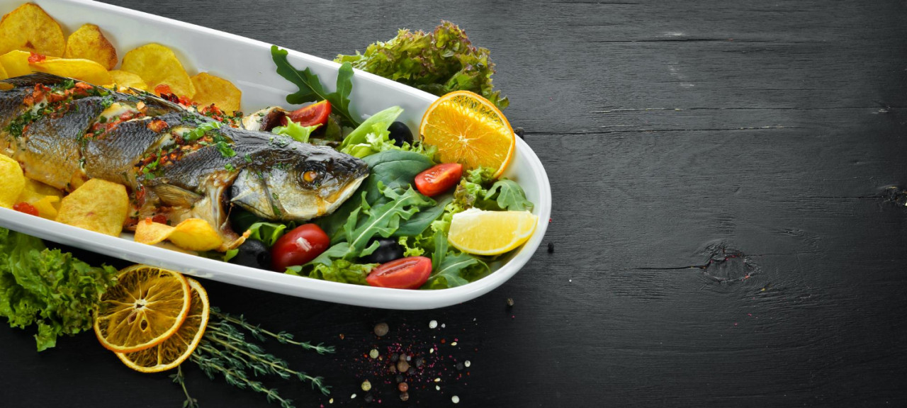 trout baked with potatoes and vegetables on a wooden background top view free copy space