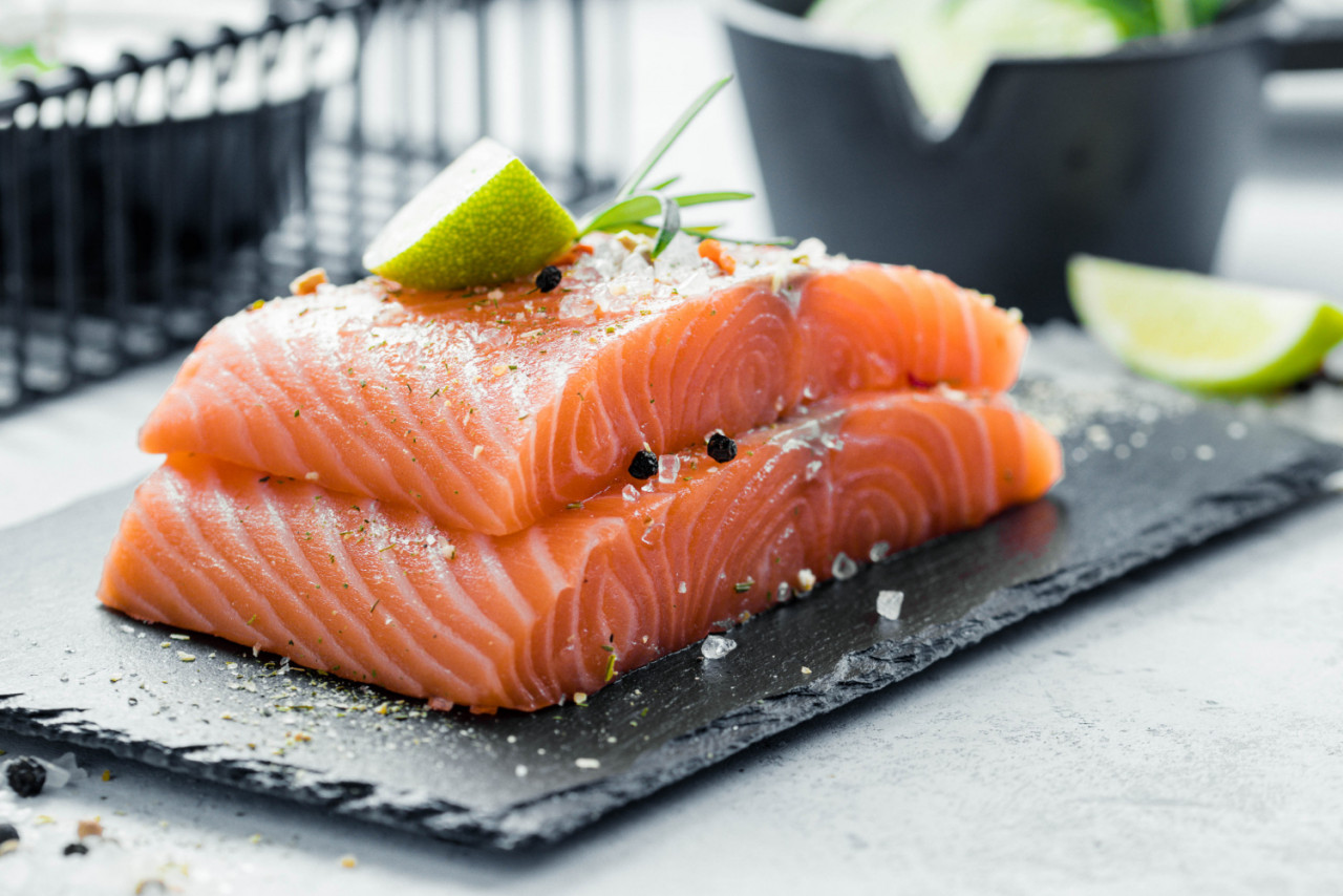 two pieces raw salmon fillet with fresh herb rosemary spices olive oil black slate plate