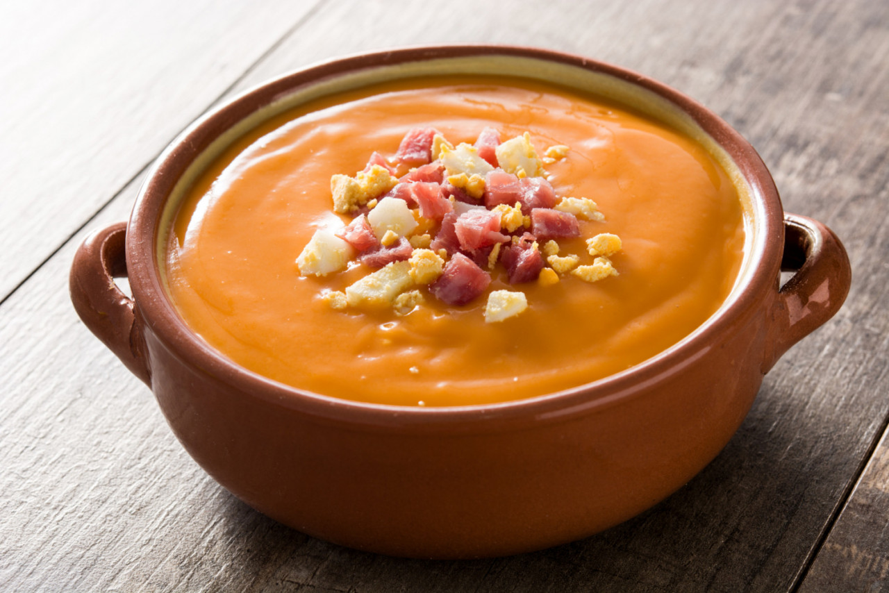 typical spanish salmorejo cream with ham egg wooden table top view