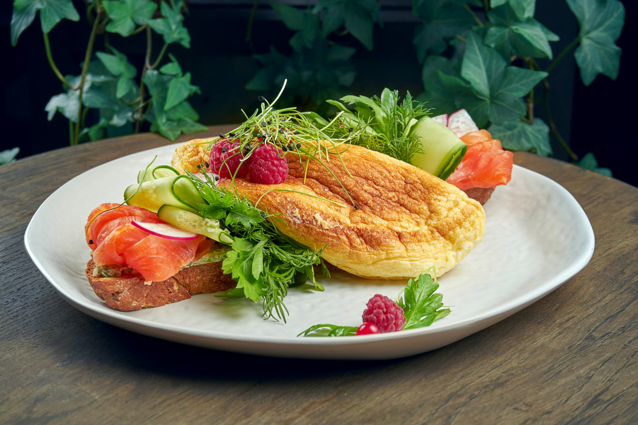 variation smorrebrod rye bread with omelette cucumbers salmon white plate wooden surface