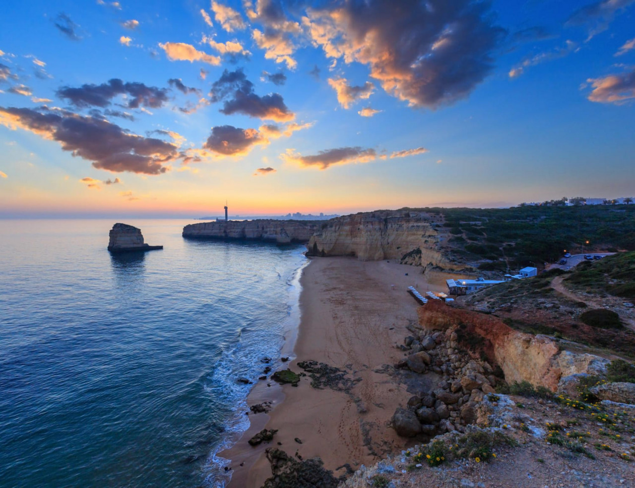 vista del tramonto sulla costa del mare con il faro di ponta do altar vista ad ovest sulla spiaggia di praia da afurada ferragudo lagoa algarve portogallo