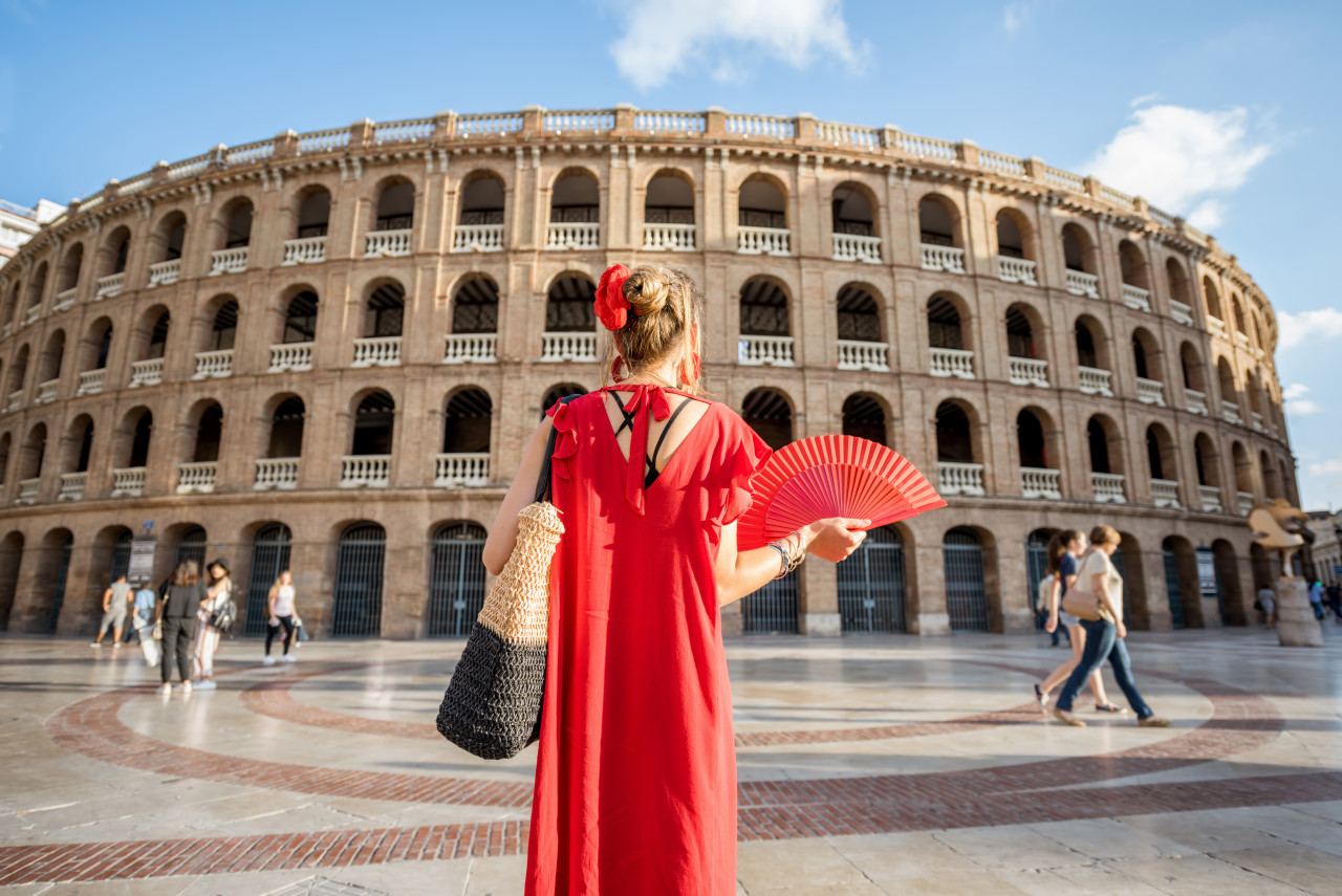 woman red dress with spanish hand fan stnading back front bullring amphitheatre valencia city spain