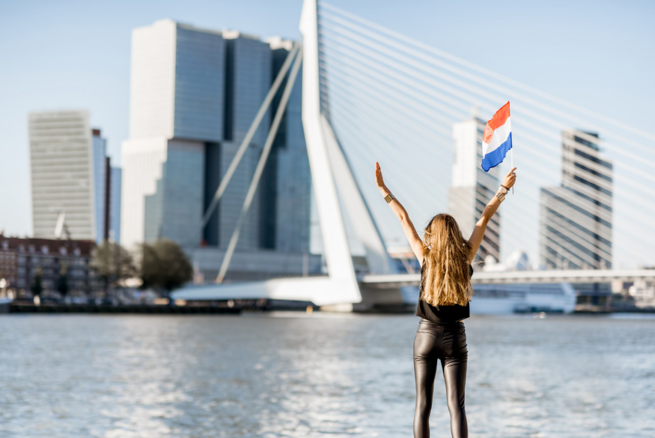 woman with dutch flag enjoying beautiful cityscape view modern riverside during morning rotterdam city