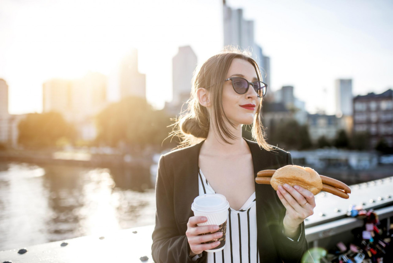 young businesswoman having snack with traditional franfurt sausage