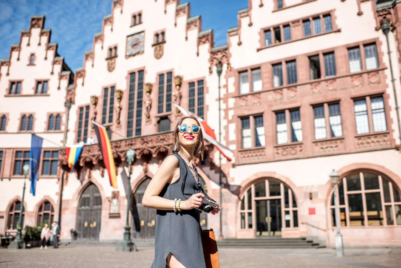 young female tourist with photo camera enjoying visiting old city center frankfurt city