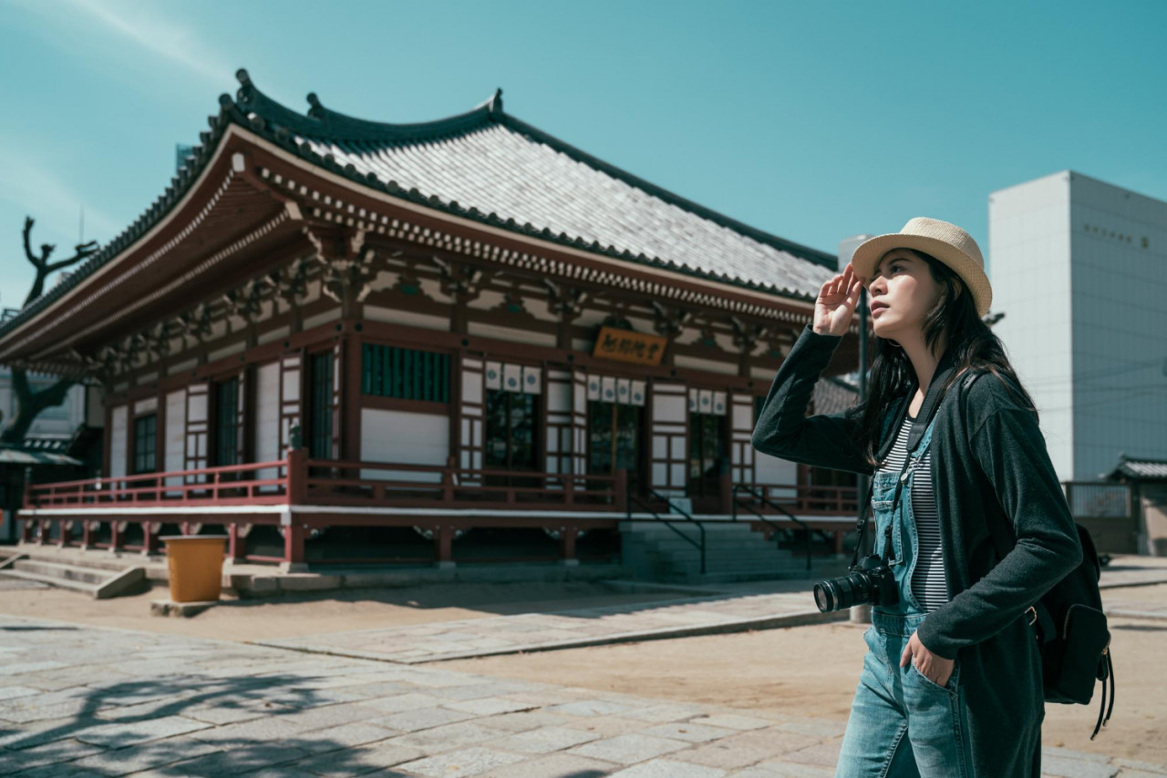 young female travel photographer with photo camera walking shitennoji temple osaka college girl tourist travel japan summer break woman backpacker relax outdoor shinto with blue sky