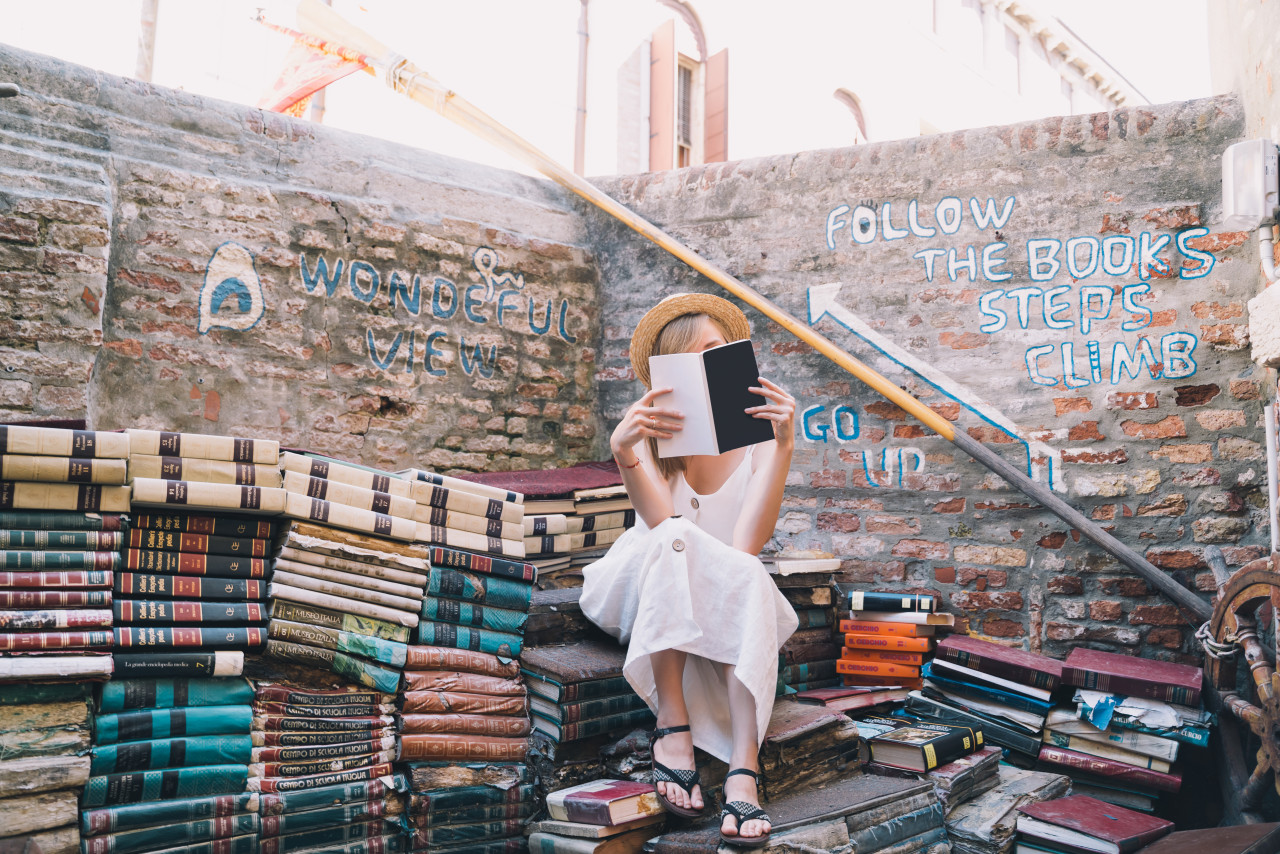 young woman choosing book ancient secondhand bookstore libreria acqua alta venice italy 1