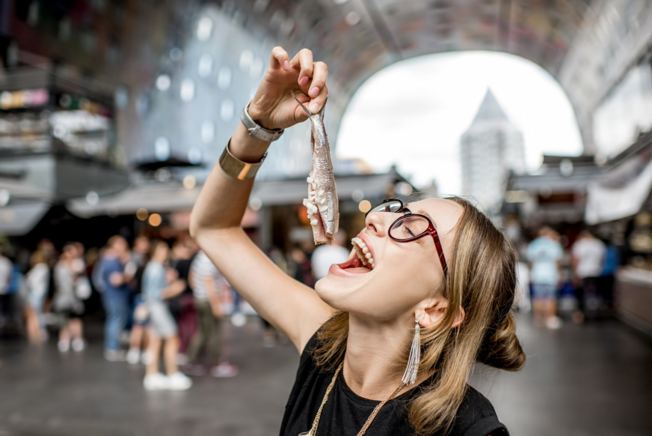 young woman eating herring with onions traditional dutch snack rotterdam market