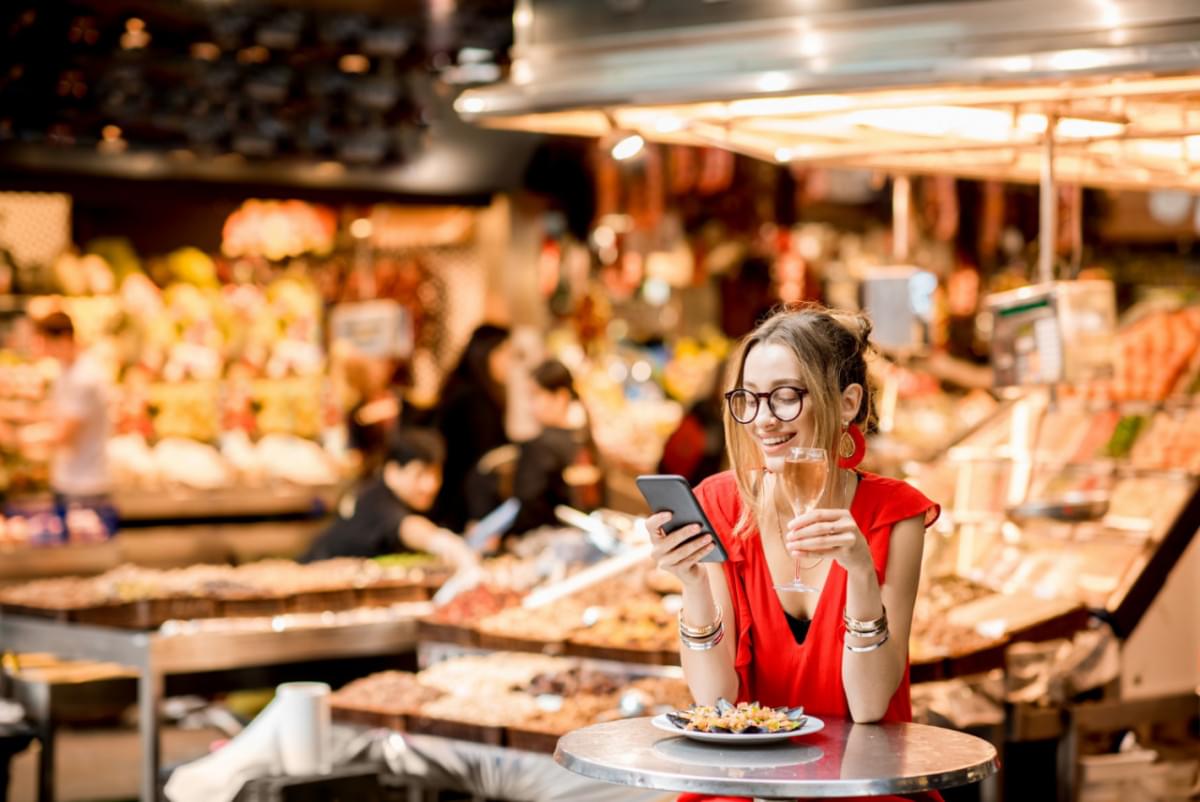 young woman red dress having lunch with mussels rose wine sitting food market