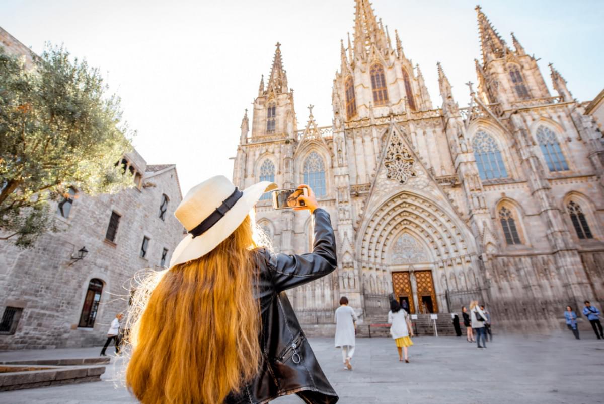 young woman tourist photographing with phone famous saint eulalia church during morning light barcelona city