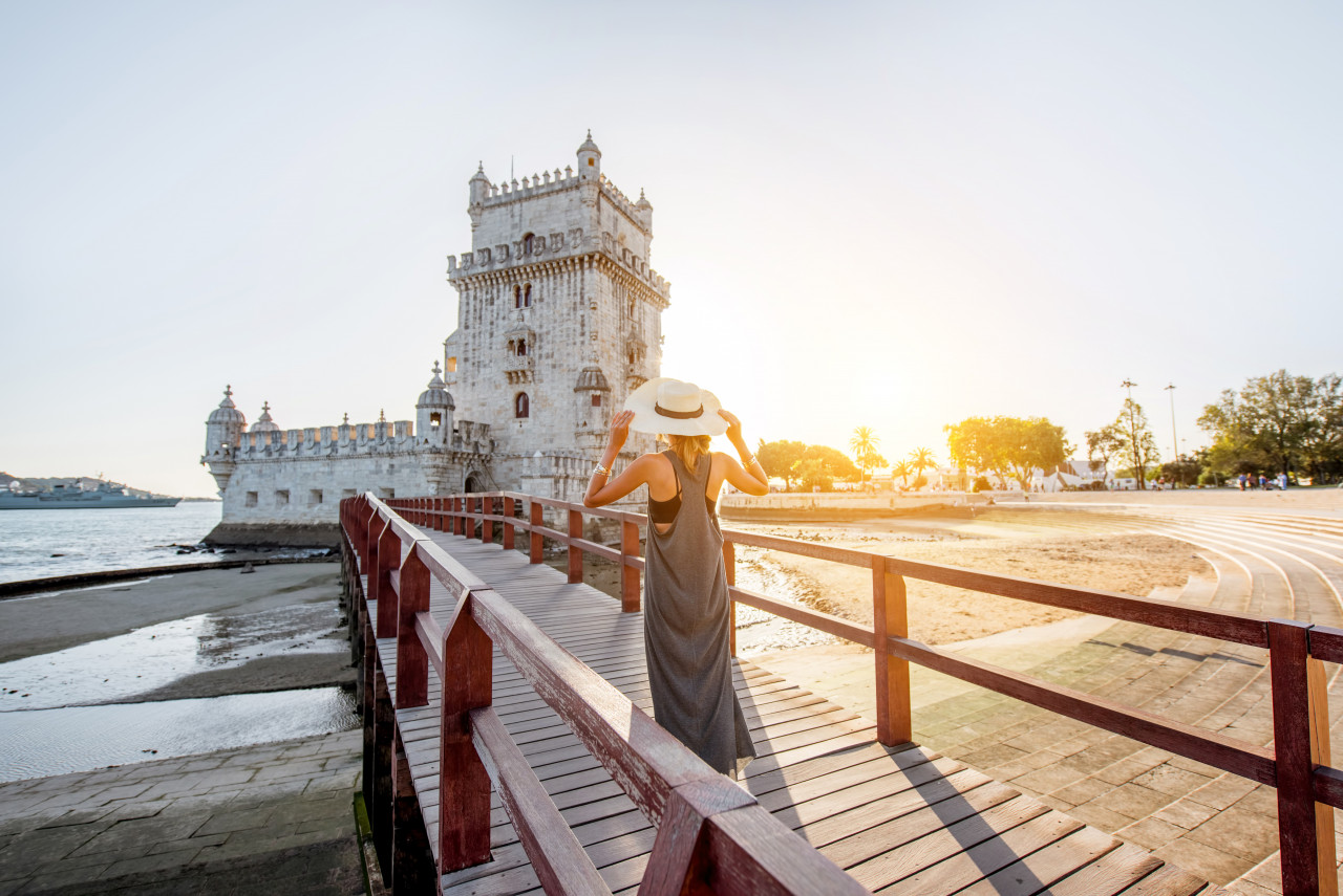 young woman tourist walking bridge belem tower riverside during sunset lisbon portugal
