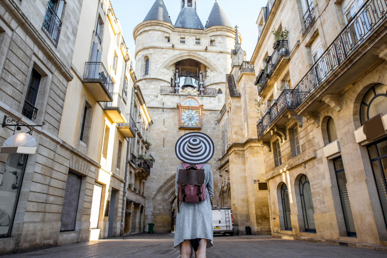 young woman tourist with big hat standing back front famous bell tower bordeaux city france